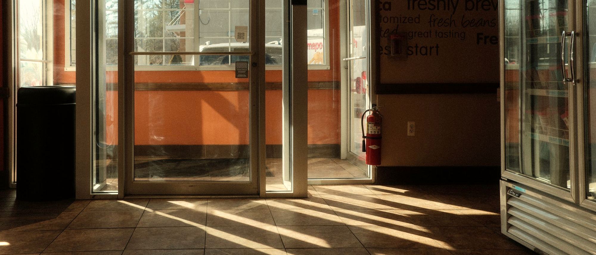 Late-afternoon sunlight across the floor of a convenience store entrance